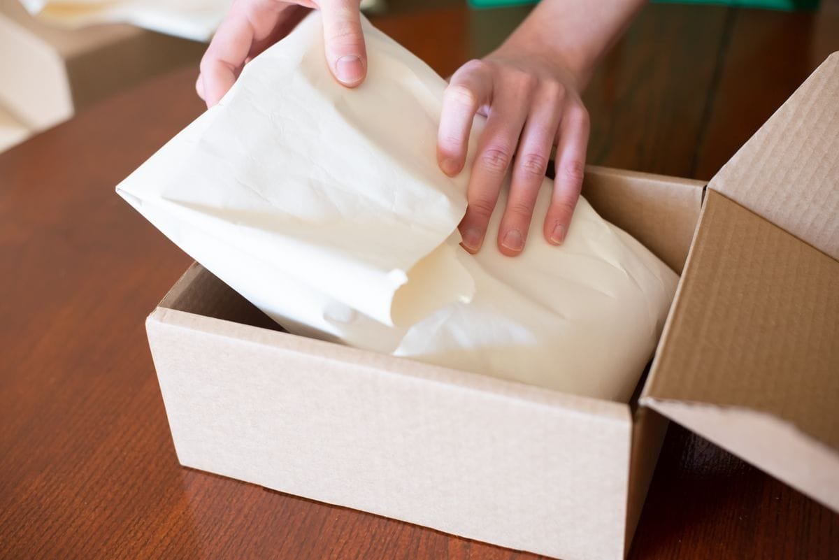 Hands packing a customer order into a cardboard shipping box
