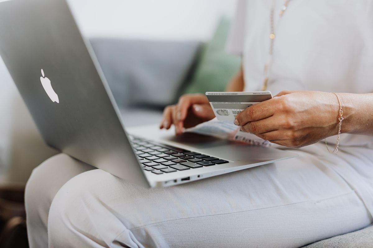 Online shopper holding a credit card while paying on a laptop